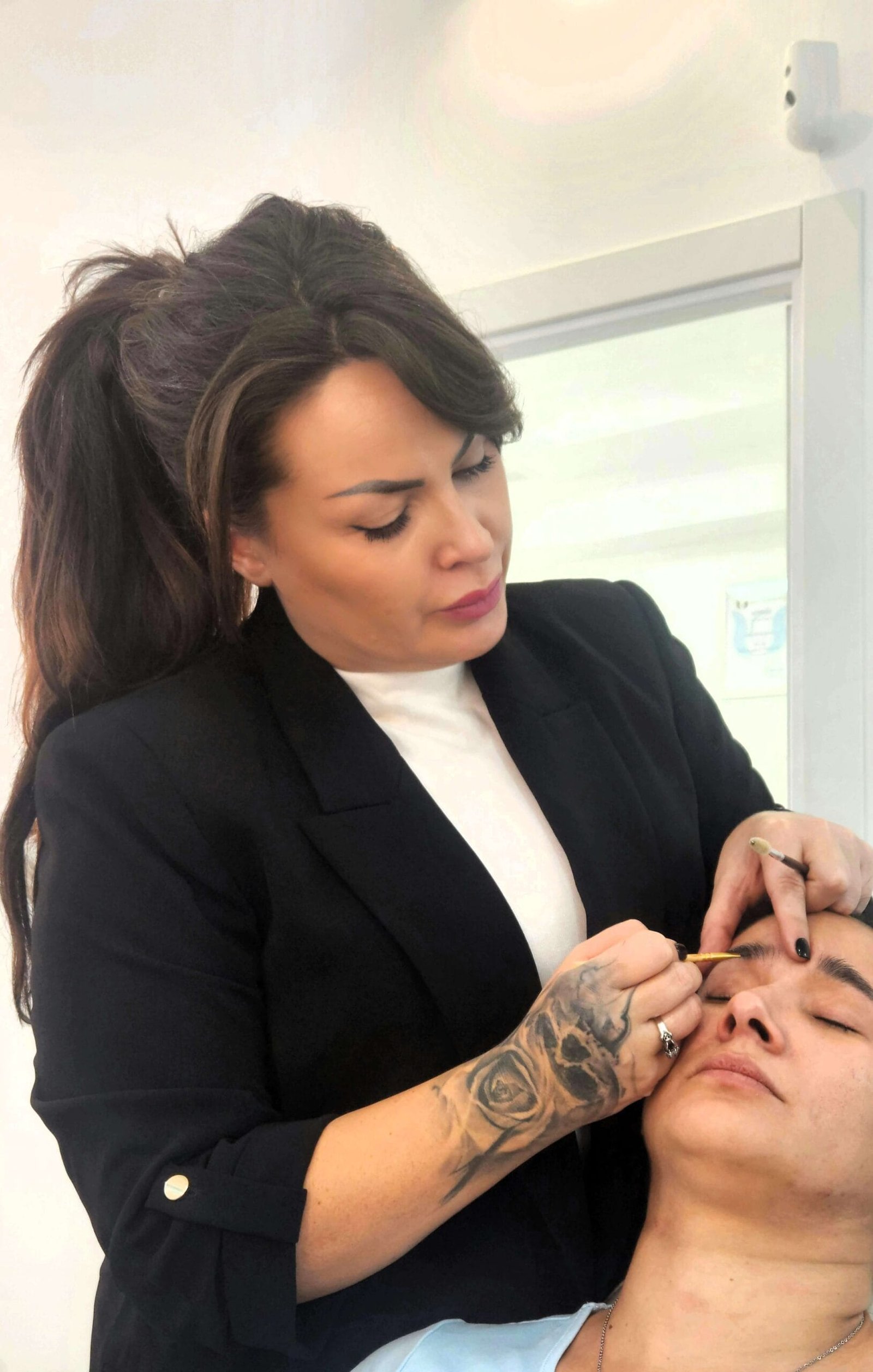 Rocío Martín Micropigmentación Estética - Rocío Martín, experta en micropigmentación, realizando un tratamiento de cejas a una clienta mientras trabaja con precisión, mostrando un servicio profesional.