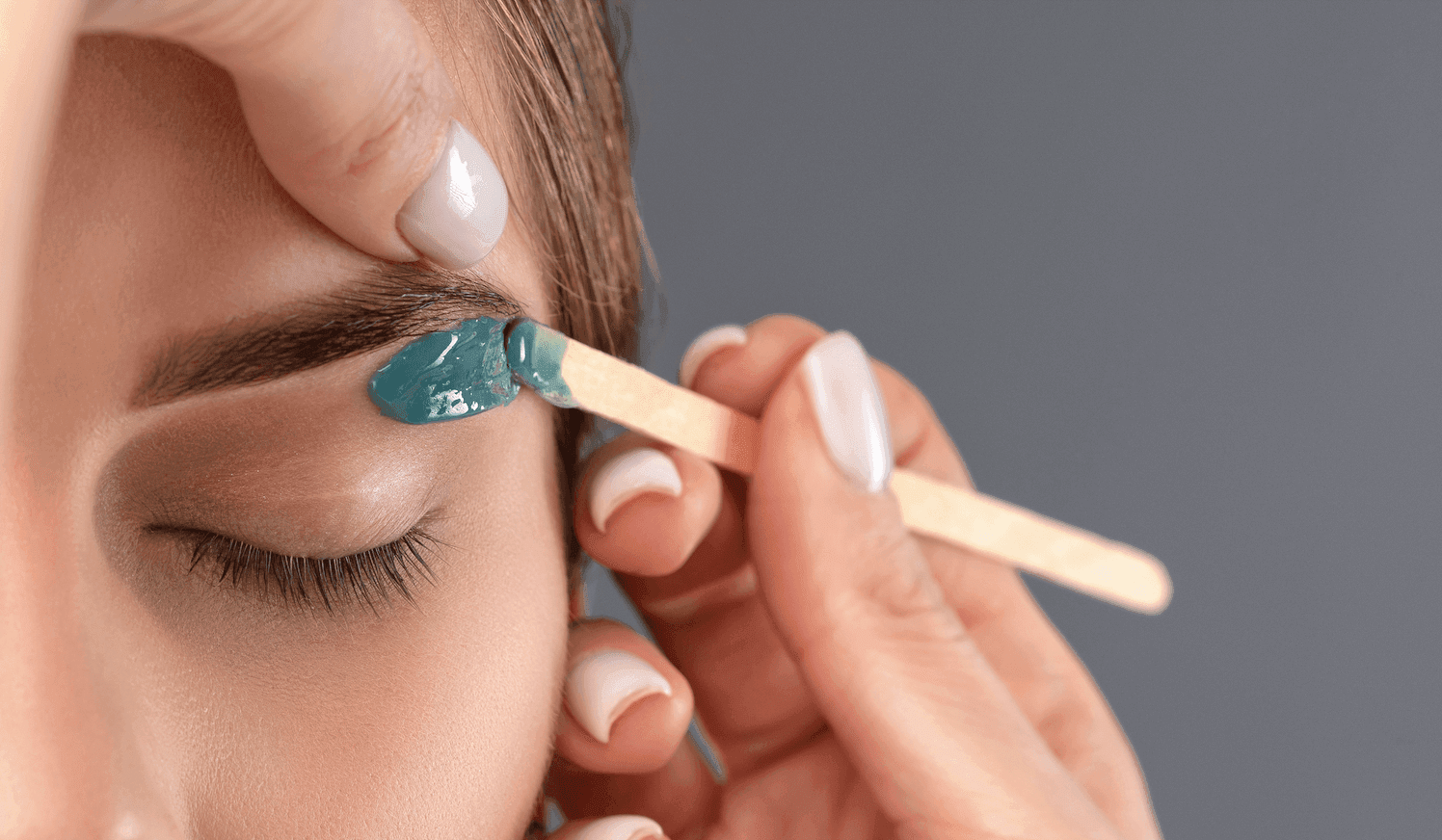 Depilación cera Aplicación detallada de cera tibia en la zona de las cejas para depilación, realizada por profesional en Rocío Martín Micropigmentación y Estética Madrid; técnica precisa y segura que define la forma natural de las cejas y cuida la piel sensible del rostro