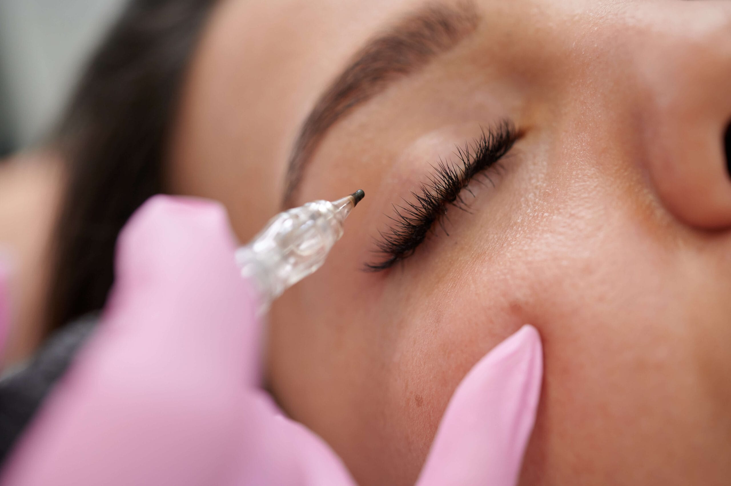 Micropigmentación Ojos Aplicación de micropigmentación en la línea de pestañas con dermógrafo; ojo femenino cerrado durante el procedimiento en Rocío Martín Micropigmentación y Estética.