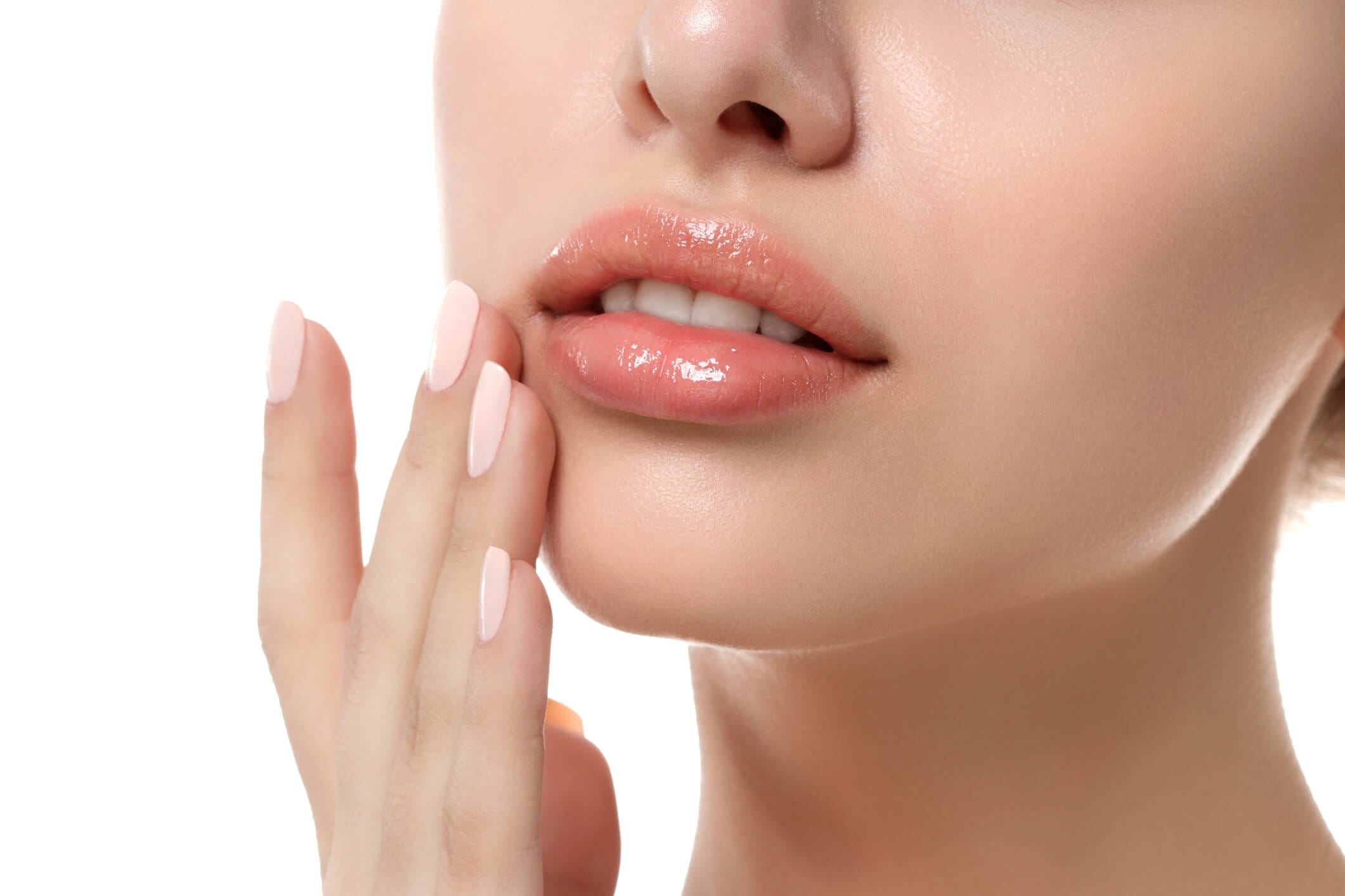 06 Labios para quien va el servicio Rocío Martín Micropigmentación Estética - Primer plano de la parte inferior del rostro de una mujer, destacando unos labios voluminosos y brillantes con un tono nude rosado. Una mano con uñas bien cuidadas y esmaltadas en color rosa claro toca suavemente la barbilla. La piel de la modelo es clara y lisa